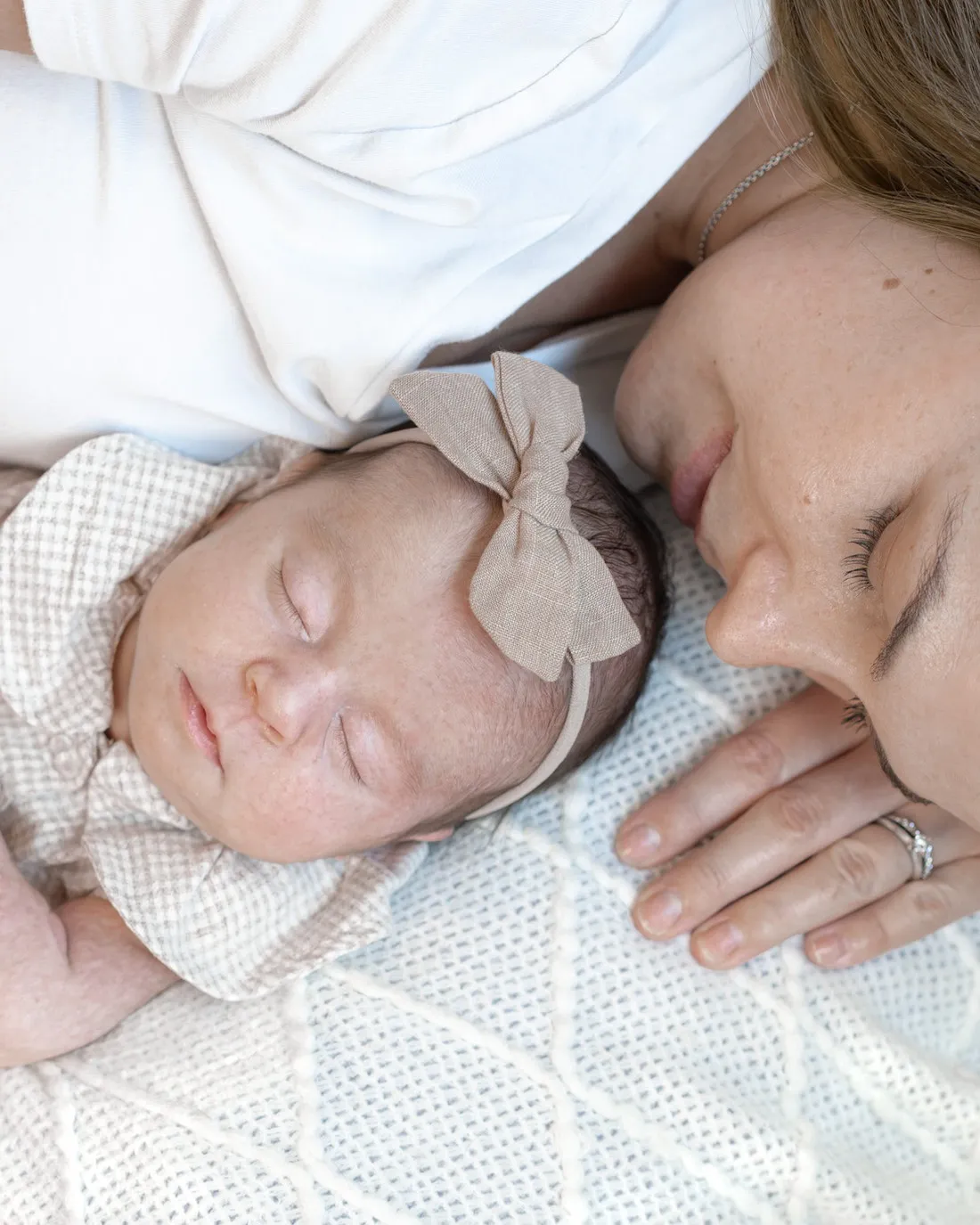 A mother resting her cheek against her sleeping newborn